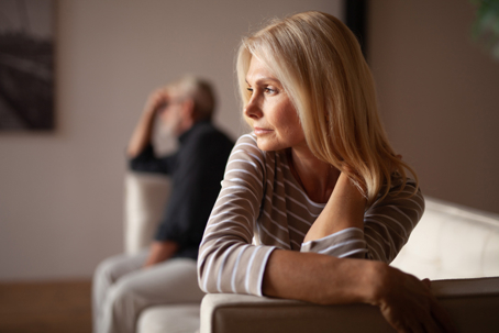 Women sitting on the couch with man blurred behind her