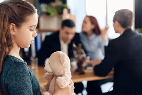 child in foreground with parents arguing in background